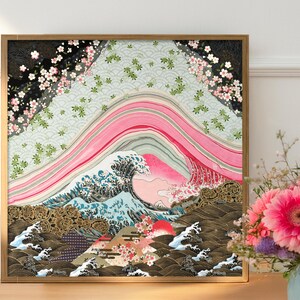Japanese inspired wave and cherry blossom paper collage art print in a natural wood frame, styled on a wooden sideboard beside a vase of fresh pink flowers, showcasing layered pink arcs, intricate blue waves, and gold patterned details.