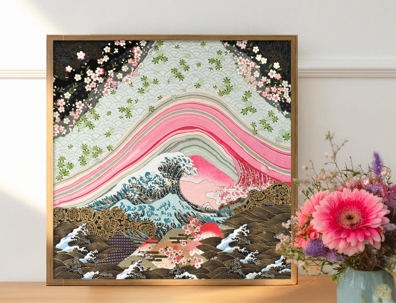 Japanese inspired wave and cherry blossom paper collage art print in a natural wood frame, styled on a wooden sideboard beside a vase of fresh pink flowers, showcasing layered pink arcs, intricate blue waves, and gold patterned details.