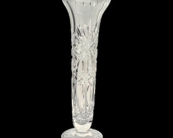 May include: A clear crystal vase with a flared top and a round base. The vase features intricate starburst and vertical line patterns, creating a textured appearance. The vase is approximately 10 inches tall.