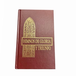 May include: A maroon-colored book with gold lettering and a decorative design. The text on the cover reads "HIMNOS DE GLORIA Y TRIUNFO". The book has a textured cover and a simple, elegant design.