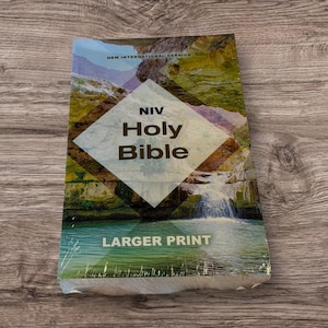 May include: A new, shrink-wrapped NIV Holy Bible with a landscape cover featuring a waterfall and mountain scene. The title "Holy Bible" is prominently displayed in large, bold letters, with "Larger Print" at the bottom.
