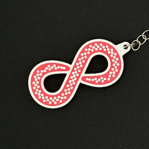 May include: A pink infinity symbol keychain with white dots. The keychain is made of a soft, flexible material.
