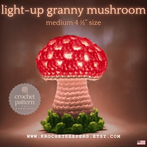 May include: A light-up, medium-sized (4.5 inches) crochet mushroom lamp. The red cap has white accents and is lit from within. The stem is light pink, and the base is surrounded by green crochet foliage. Text reads "light-up granny mushroom".