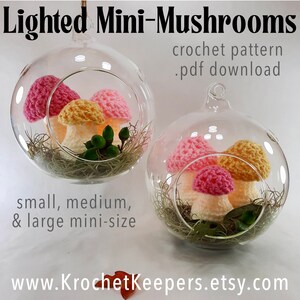 May include: Two glass terrariums each contain crochet mushrooms in pink, yellow, and white. The terrariums are filled with moss and greenery. Text reads "Lighted Mini-Mushrooms" and "crochet pattern .pdf download". The website address is www.KrochetKeepers.etsy.com.