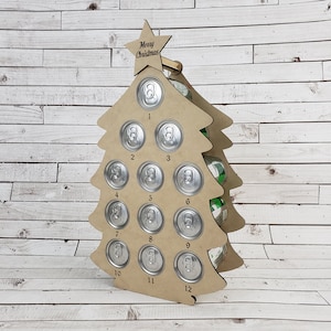 Könnte beinhalten: Ein hölzerner Weihnachtsbaum-förmiger Dosenhalter mit 12 Fächern für Dosen. Der Baum ist mit einem Stern oben und den Worten "Frohe Weihnachten" auf dem Stern verziert. Der Baum ist aus braunem Holz und hat eine natürliche Oberfläche.