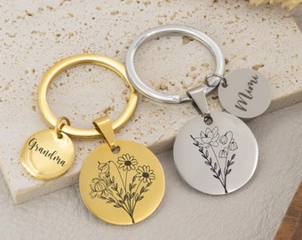 May include: Two gold and silver keychains with floral designs and engraved names. The gold keychain has a tag that says "Grandma" and the silver keychain has a tag that says "Mimi".