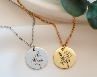 May include: Two delicate silver and gold necklaces with round pendants featuring engraved floral designs. The pendants are both circular and feature a single stem with multiple flowers.