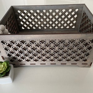 May include: A gray wooden storage box with a decorative geometric pattern. The box has a rectangular shape and is made of wood with a distressed finish.