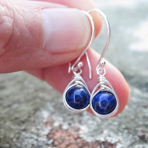 May include: A pair of silver wire wrapped earrings with blue lapis lazuli gemstone beads.