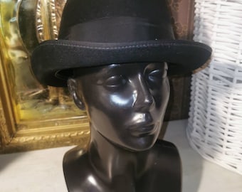 May include: A black felt bowler hat with a black grosgrain ribbon band. The hat is sitting on a black mannequin head.