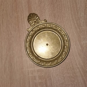 Peut inclure: Un plateau décoratif en métal doré avec un bord festonné et des motifs floraux complexes. Le plateau est circulaire et possède un bord surélevé.