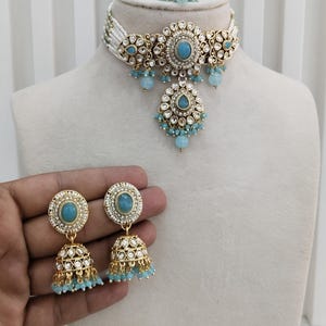 May include: Sky blue jewelry set featuring a choker necklace, earrings, and a ring. The set includes a necklace with a central sky blue stone and matching earrings with dangling beads. The text "Glam jewelrys" is visible.