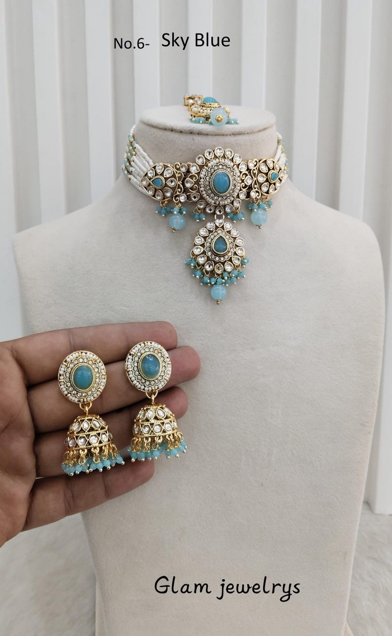 May include: Sky blue jewelry set featuring a choker necklace, earrings, and a ring. The set includes a necklace with a central sky blue stone and matching earrings with dangling beads. The text "Glam jewelrys" is visible.