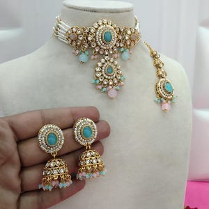 May include: An ornate gold-toned jewelry set featuring a choker necklace, earrings, and a headpiece. The set includes turquoise-colored stones, white beads, and pink and blue accents. The text "No. 4 - Sea Green Pink" is visible.
