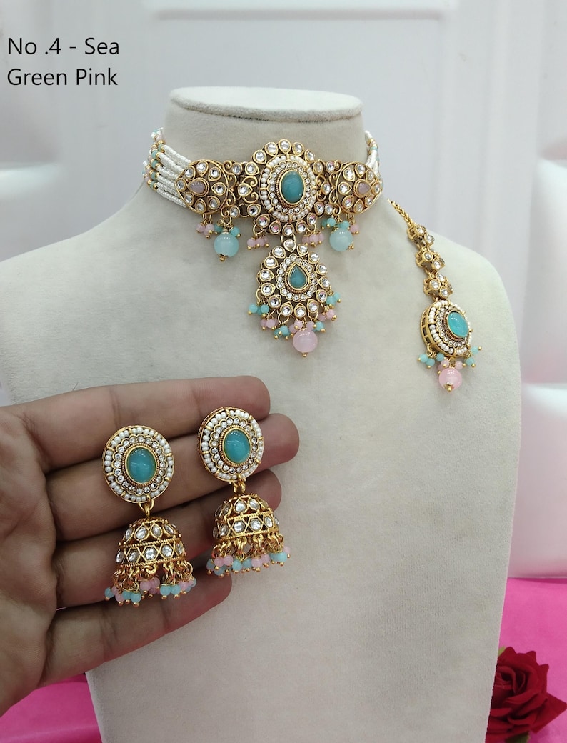May include: An ornate gold-toned jewelry set featuring a choker necklace, earrings, and a headpiece. The set includes turquoise-colored stones, white beads, and pink and blue accents. The text "No. 4 - Sea Green Pink" is visible.