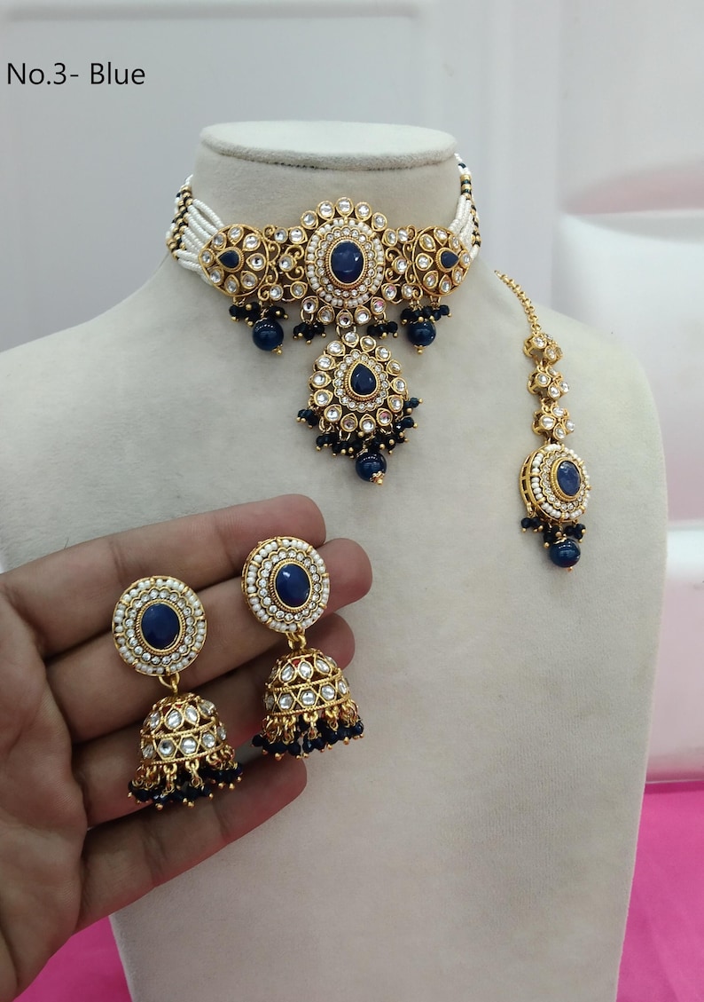 May include: A blue and gold jewelry set, including a choker necklace, earrings, and a headpiece. The set features blue gemstones and white accents. The earrings are held by a hand. The text "No.3- Blue" is in the top left corner.