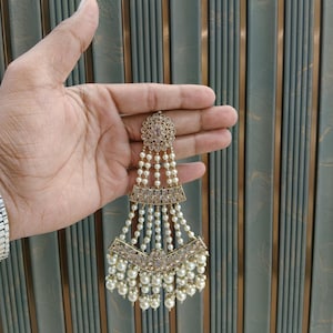 May include: Antique gold-colored hair accessory with a floral design and dangling pearls. The piece is held in a hand, showcasing its intricate details. The text "No.5- Antique gold" is visible in the image.