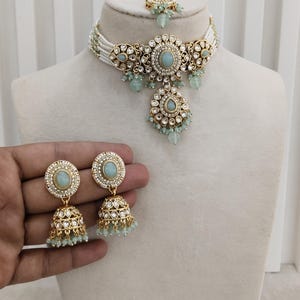 May include: Sea green jewelry set with a necklace, earrings, and headpiece. The set features gold-toned metal with sea green stones and white beaded accents. The text "No.7- Sea Green" and "Glam jewelrys" are visible.