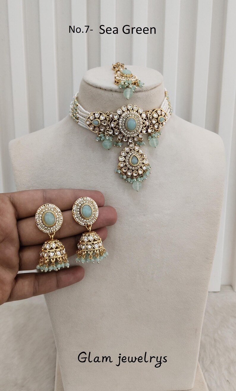 May include: Sea green jewelry set with a necklace, earrings, and headpiece. The set features gold-toned metal with sea green stones and white beaded accents. The text "No.7- Sea Green" and "Glam jewelrys" are visible.