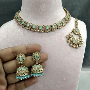 Op de afbeelding: Zeegroene sieradenset met een ketting, oorbellen en een hoofdband. De set heeft een goudkleurige metalen basis met zeegroene en heldere stenen accenten. De oorbellen zijn klokvormig met bungelende kralen. De ketting en hoofdband hebben een bijpassend ontwerp.