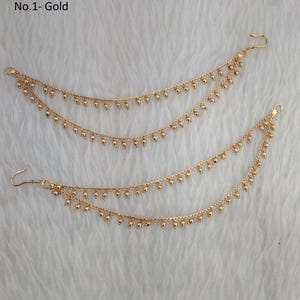 Op de afbeelding: Een paar gouden oorsieraden met kleine ronde kralen die eraan hangen. De kettingen hebben een haak aan het einde om aan het oor te bevestigen.