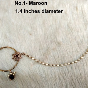 May include: A gold nose ring with a maroon gemstone and a pearl chain. The ring is 1.4 inches in diameter. No. 1 - Maroon.