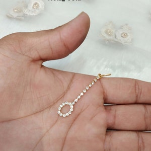 Op de afbeelding: Een goudkleurig, delicaat haaraccessoire met een cirkelvormig ontwerp en een rij heldere, sprankelende stenen. Het accessoire is ontworpen om op het hoofd te worden gedragen. De tekst "No.2_ Gold" is zichtbaar.