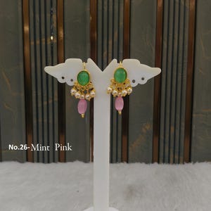 May include: A pair of gold-tone earrings featuring a central oval mint green stone, a row of small white pearls, and a single dangling pink oval bead. The text No.26-Mint Pink is visible on the left side of the image near the earring display stand.