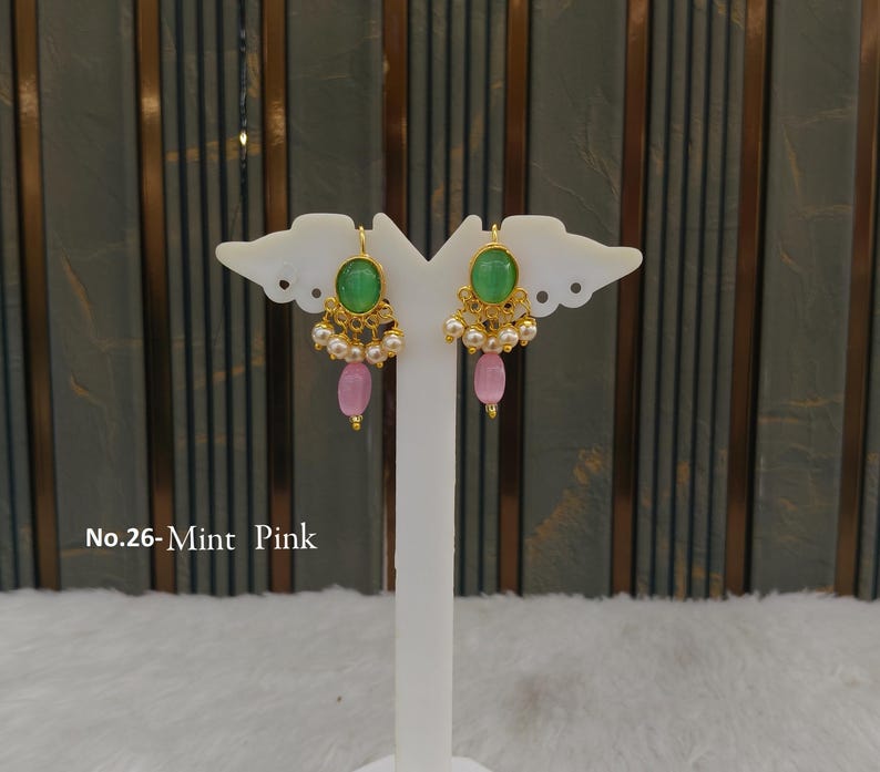 May include: A pair of gold-tone earrings featuring a central oval mint green stone, a row of small white pearls, and a single dangling pink oval bead. The text No.26-Mint Pink is visible on the left side of the image near the earring display stand.
