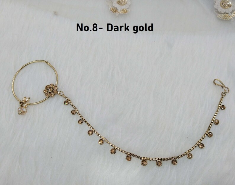 May include: Gold nose ring with a chain and small stones. The ring has a flower design and the chain has a hook closure. The text "No.8 - Dark gold" is visible in the image.