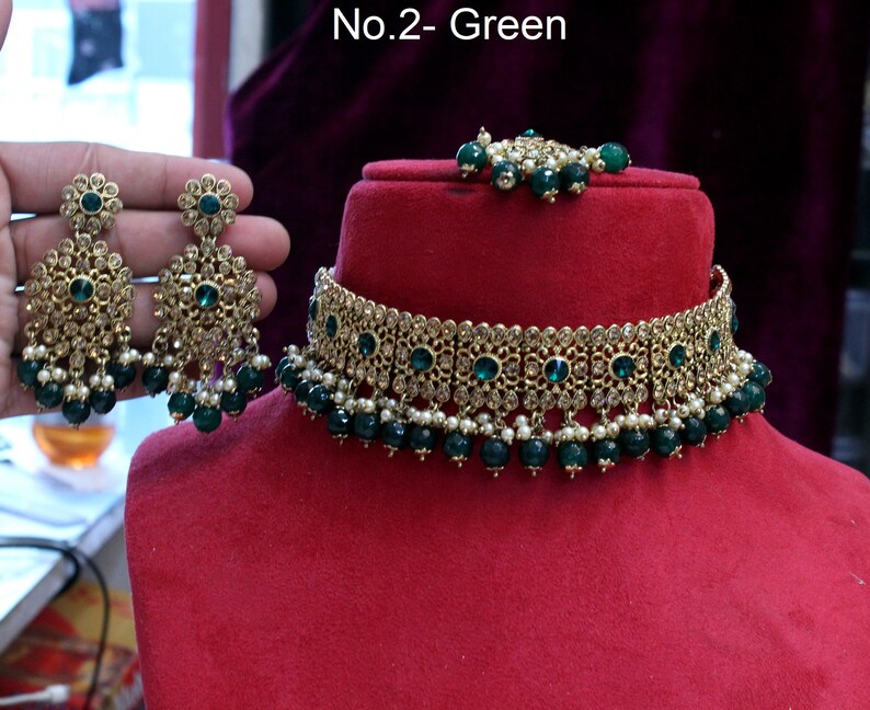 May include: A gold choker necklace with green and white beads, a matching pair of earrings with green stones, and a small green and white bead necklace. The text "No.2 - Green" is visible in the image.