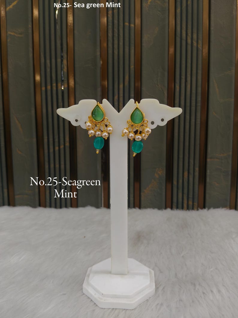 May include: A pair of gold-toned earrings featuring a teardrop-shaped sea green mint stone at the top, accented with small white pearls and a dangling round sea green mint bead. The text No.25- Sea green Mint is visible in the image.