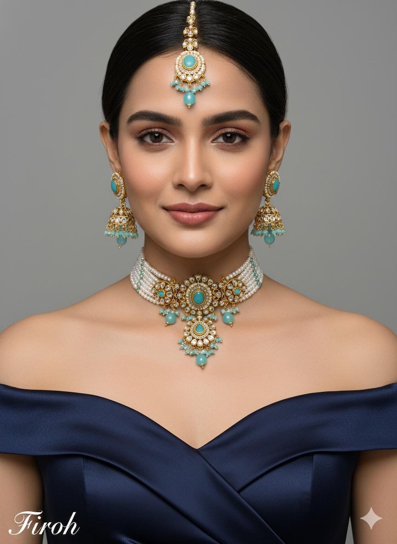 May include: An ornate gold-toned jewelry set featuring turquoise-colored stones and white pearls. The set includes a necklace, earrings, and a headpiece. The necklace has a central pendant with a floral design. The earrings are bell-shaped.