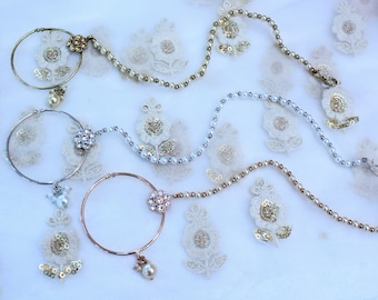May include: Three silver and gold nose rings with pearl and rhinestone accents. The rings are on a white background with lace.