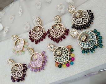 May include: A set of eight pairs of dangle earrings with a variety of colored beads and stones. The earrings feature a gold-tone metal base with a circular design and a floral motif. The beads are in shades of pink, green, purple, and red.