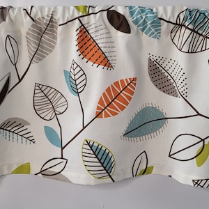 May include: A white valance with a repeating pattern of stylized leaves in shades of brown, orange, green, and blue.