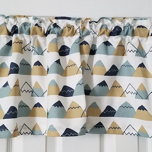 May include: A white valance with a repeating pattern of blue, yellow, and navy blue mountains. The valance has a ruffled edge.