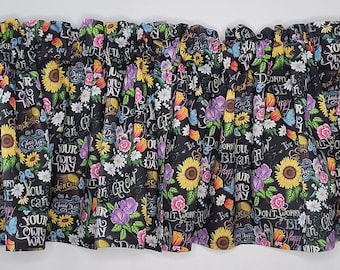 Könnte beinhalten: Schwarzer floraler Volant mit Sonnenblumen, Rosen und Schmetterlingen. Der Stoff zeigt inspirierenden Text in Weiß. Der Volant ist oben gerafft und hat eine Stangentasche zum einfachen Aufhängen. Eine dekorative Fensterdekoration.