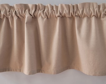 Pode incluir: Uma valance bege com uma borda superior franjada. A valance é feita de um tecido macio e texturizado.