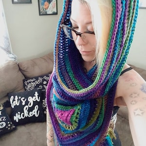 Pode incluir: Uma gola de croch&ecirc; colorida com capuz e franjas. A gola &eacute; feita em tons de azul, verde, roxo e rosa.