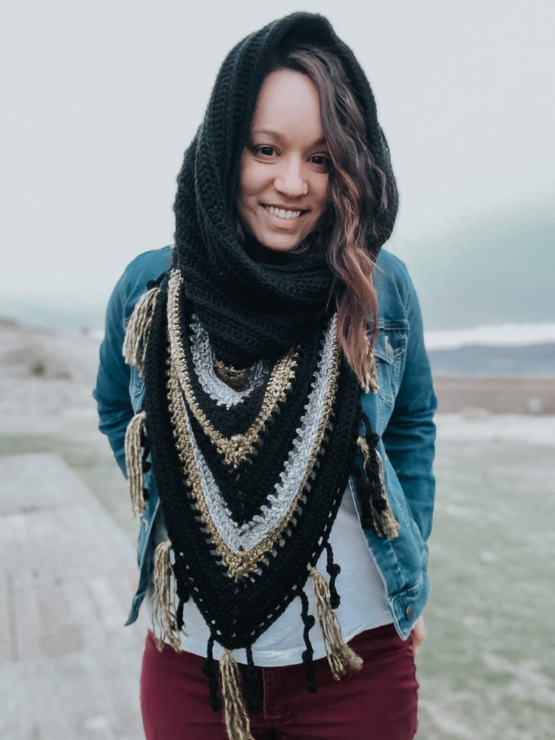 Pode incluir: Um xale de croch&ecirc; preto e dourado com franjas. O xale &eacute; usado por uma pessoa com cabelo castanho comprido e uma jaqueta de ganga.