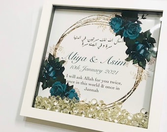 May include: A white framed picture with a gold and blue floral design. The text in the picture reads "أسأل الله لك مرتين في الدنيا سرة وفي الجنة مرة Aliya & Asim 10th January 2021 I will ask Allah for you twice, once in this world & once in Jannah"