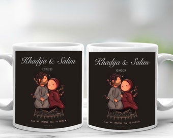 Op de afbeelding: Twee witte keramische mokken met een zwarte afbeelding met een stel en de namen "Khadija & Salim" en de datum "12/02/23". De mokken hebben een gebogen handvat en een decoratief ontwerp.
