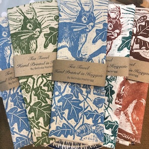 May include: Four tea towels with a squirrel design. The towels are hand-printed in Huggate, England. The towels are in green, blue, brown, and orange.