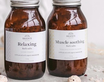 Puede incluir: Dos frascos de vidrio ámbar con tapas plateadas que contienen 400g de sales de baño. La etiqueta izquierda dice Shanti Naturals Relaxing Bath salts, lavender, bergamot, 100% natural with organic essential oils. La etiqueta derecha dice Muscle soothing.