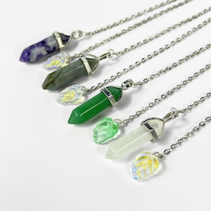 Puede incluir: Una colección de collares con colgantes de piedras preciosas. Cada collar presenta un colgante de cristal de diferente color, incluyendo púrpura, verde y blanco, con una cadena plateada y un dije de hoja decorativo. Los colgantes miden aproximadamente 3,8 cm de largo.