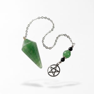 May include: A green faceted gemstone pendulum attached to a silver-toned metal chain. The chain features a round silver-toned pentagram charm, a single green spherical bead, and two smaller black faceted beads near the end of the chain.