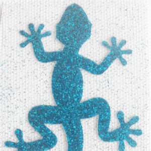 May include: A turquoise glitter gecko silhouette with a curled tail.