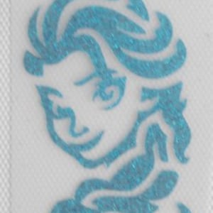Puede incluir: Un parche de planchado de brillo azul con una imagen estilizada de Elsa de la película Frozen. La imagen muestra la cara y el cabello de Elsa, con su cabello fluyendo detrás de ella.