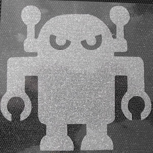 Könnte beinhalten: Ein grauer Roboter mit glitzernder Textur. Der Roboter hat zwei Antennen, zwei Augen und zwei Arme mit Händen. Der Roboter steht auf einem schwarzen Hintergrund.
